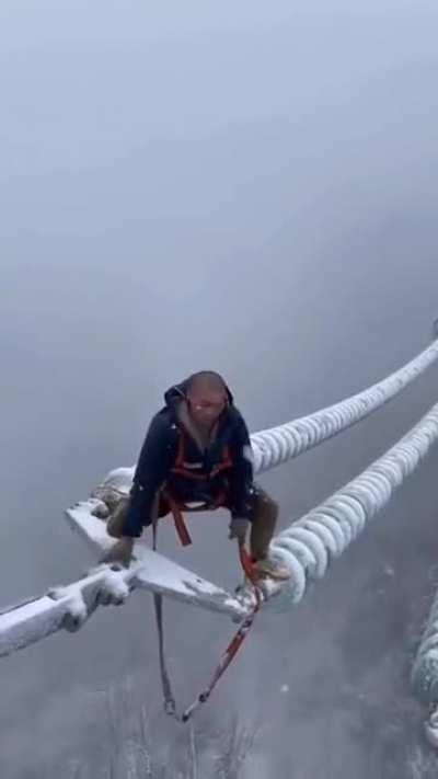 Chinese worker fixing power in the middle of a storm