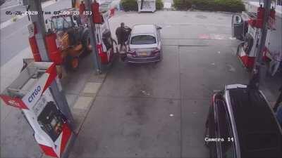 Guy overfills his car and gas spills on his shoes, gets mad and decides to attack the pump