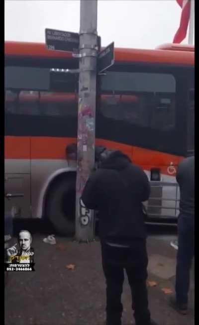 Woman tries to squeeze past a bus and a pole. She doesn't make it. 