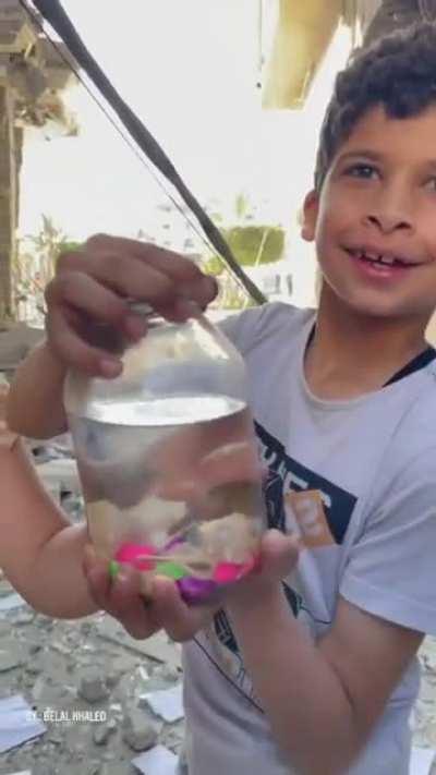 Palestinian children happy after rescuing a fish from their destroyed home.