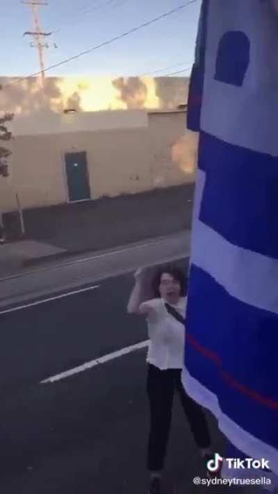 Girl rips Trump flag off truck and yells at the people in it.