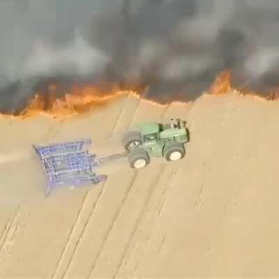 Farmer creating a buffer around his land as a wildfire closes in