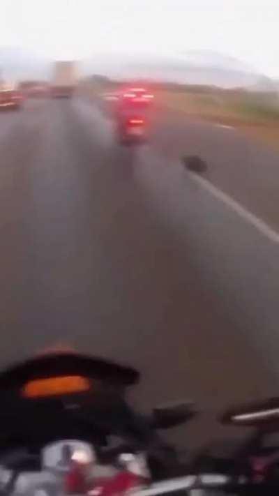A tire comes outta nowhere and knocks a guy on his bike off of his bike.