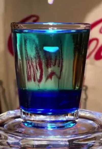 This is called the 'Blue Jellyfish Shot' and you obtain it by layering drinks with different densities and specific gravities..