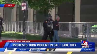 Riot cop shoves senior to the ground for no reason.