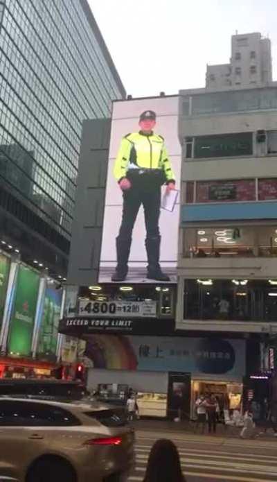 Bizarre and cringey multi-story tall video wall warning from the HKPF to look at traffic lights before crossing the road. [0:23]