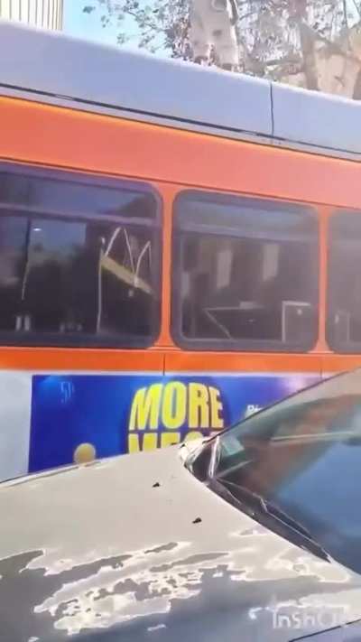 Man seen climbing and doing acrobatic flips on top of LA Metro bus while another guy starts punching and kicking the bus.