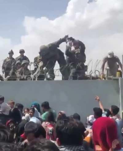 Mother handling baby to US Marines in Afghanistan
