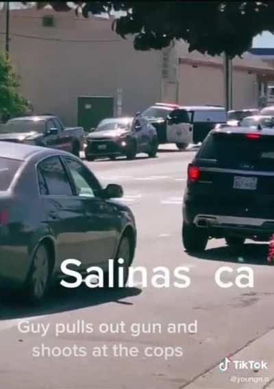 Man pulls out gun and starts shooting at the cops. The cops return fire.