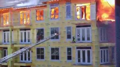 Construction worker cornered by a fire at the top of building