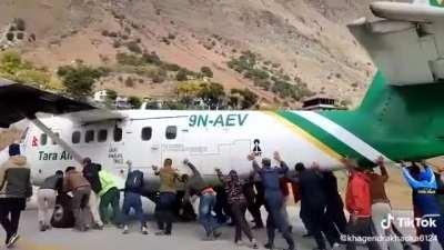People pushing aeroplane away from runway as its engine malfunctioned while taking off.