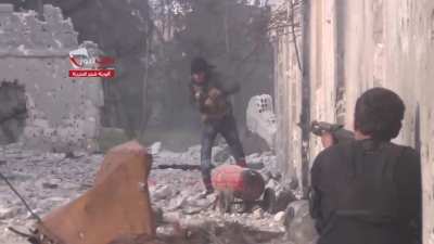 Opposition fighters working together to toss a large improvised explosive at an SAA controlled building - Bustan al-Basha - 4/16/2014