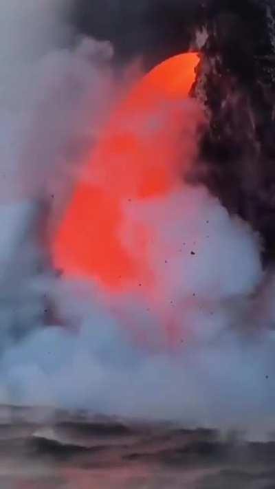 Molten lava rushing into an ocean like a waterfall