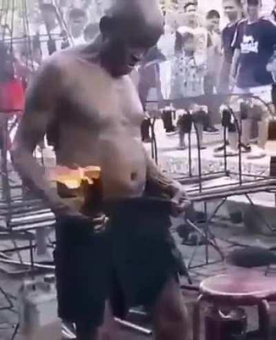 Man puts a burning stick in his pants.