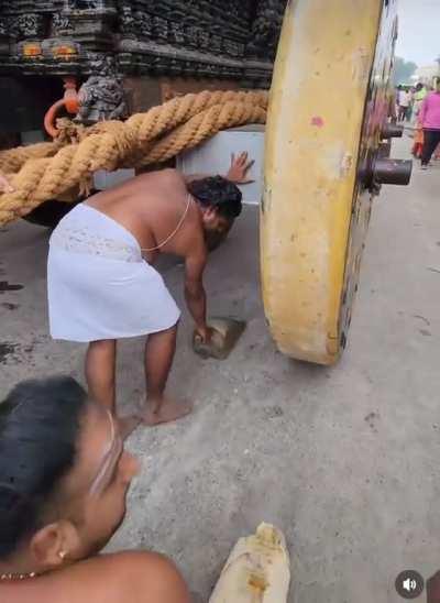 Man using a small wooden wedge to steer a massive shrine.