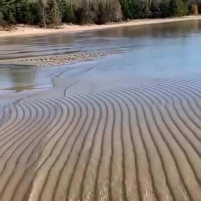 Waves going over sand without disturbing it.