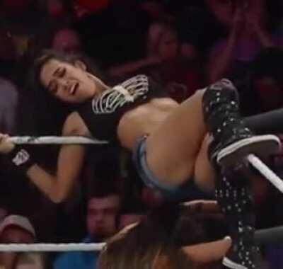 Helpless AJ draped over the top rope writhing in pain