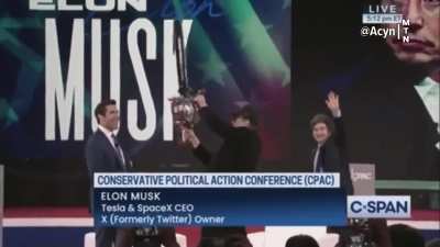 Musk swings around a chainsaw on stage to symbolize his rampage through the federal government, cutting jobs and programs