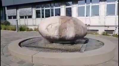 A massive boulder slipping around on top of a fountain