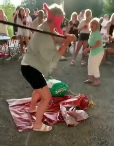 Standing in front of a blindfolded person trying to hit a piñata