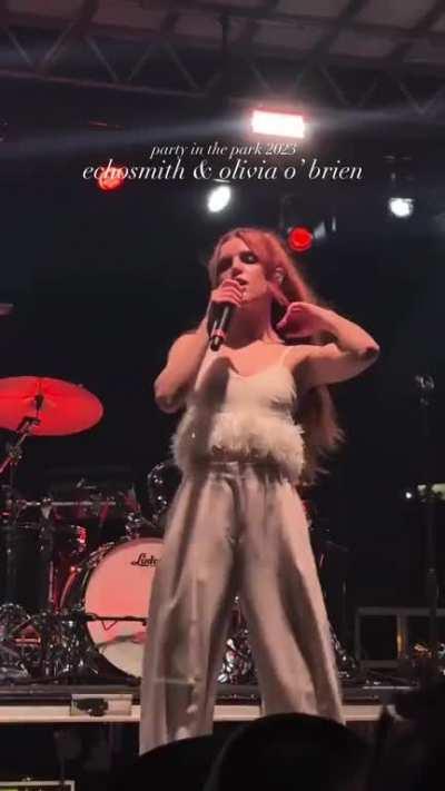 Drumming, singing & flipping her hair during a performance (April 2023)