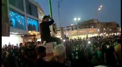 Iran: a woman sits on a utility box and cuts her hair in Kerman to protest Masha Amini's murder. Protesters chant, 
