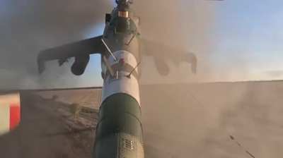 Tail view of a Ukrainian Mi-24 attack helicopter firing unguided rockets at a Russian position.