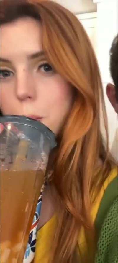 Sipping on her cold drink and doing a shoulder roll (June 2023)