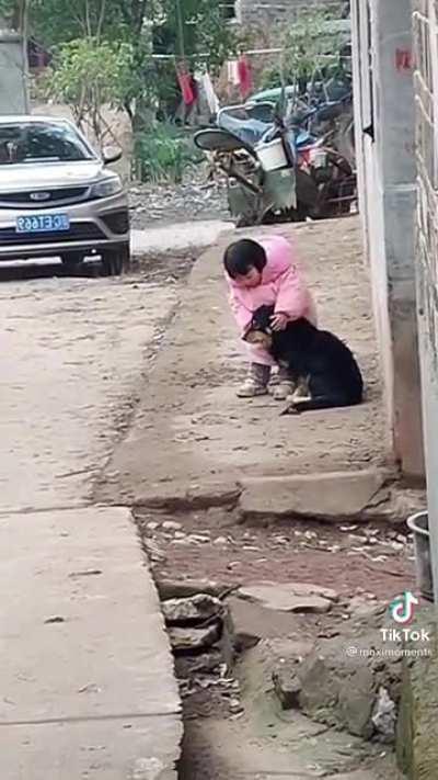 Little girl covers dogs ears so he can't hear the fireworks.