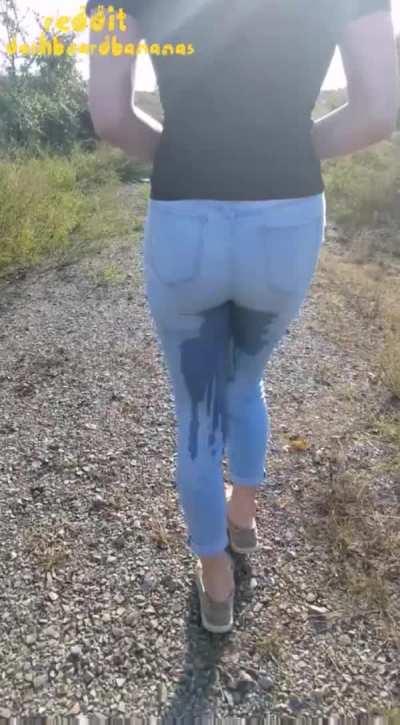 Wetting her jeans while walking on the side of the road