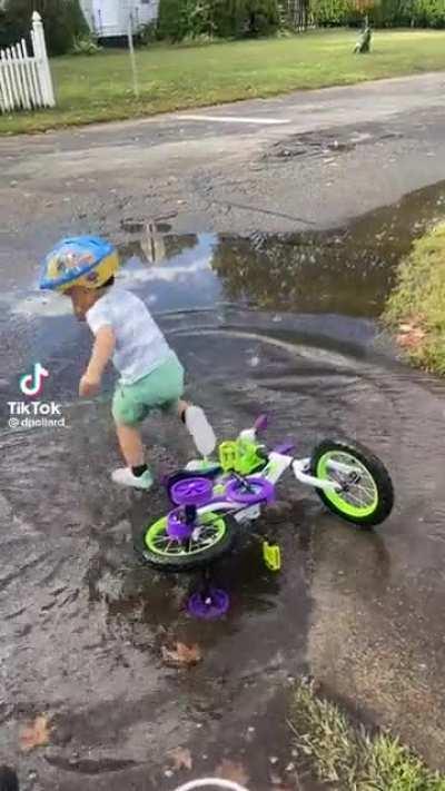 Little kid drives himself into a puddle and then falls in puddle