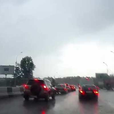 Lightning strikes a moving car in the middle of the road.
