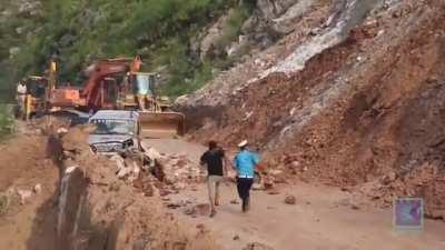Just a big boulder falling on a line of vehicles and missing them.