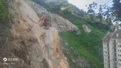Someone deploys an excavator for rock splitting right at the rough edge of a 200 foot cliff! [CN]
