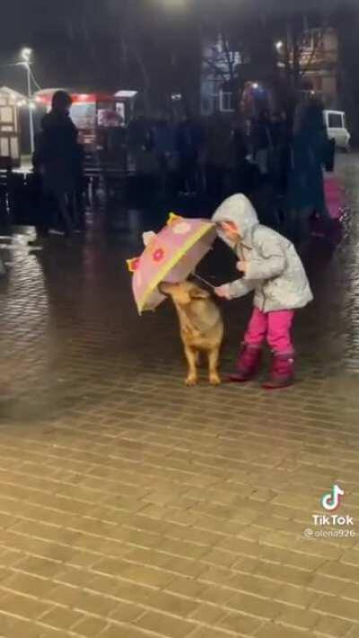 This little girl protecting a dog from the rain is so adorable