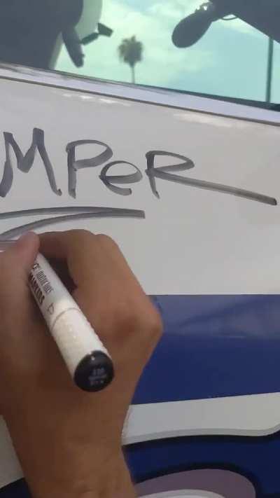 stamper writes his signature on a police car with a dry erase marker