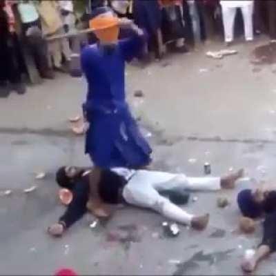 Laying on the ground while another guy hits melons with a big hamer