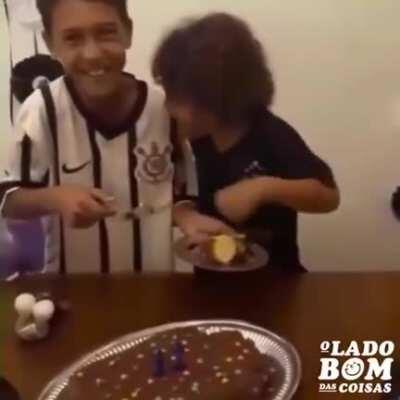 Little brother's reaction upon receiving the first piece of his brother's birthday cake.