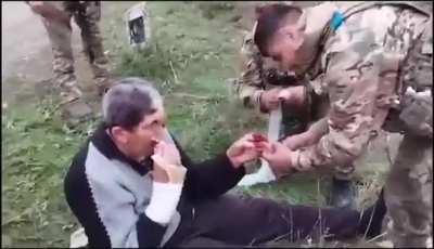 Azerbaijani Soldiers providing first aid and food to what looks like a mentally ill armenian person.