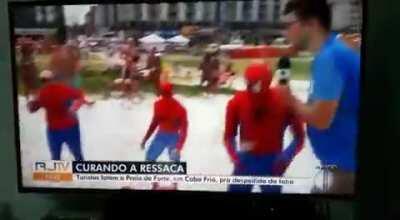 A reporter was talking about the amount of poeple coming to the beach when a group of spider-mans came into frame dancing, jumping and rolling
