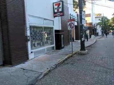 Sunlight hitting a pool on top of a motel making a rainbow on the sidewalk