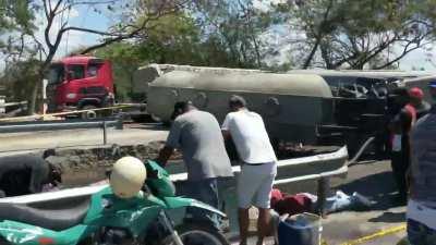 People wading in a pool of gasoline beside a wrecked fuel truck to get free buckets of gas. Near La Vega, Dominican Republic