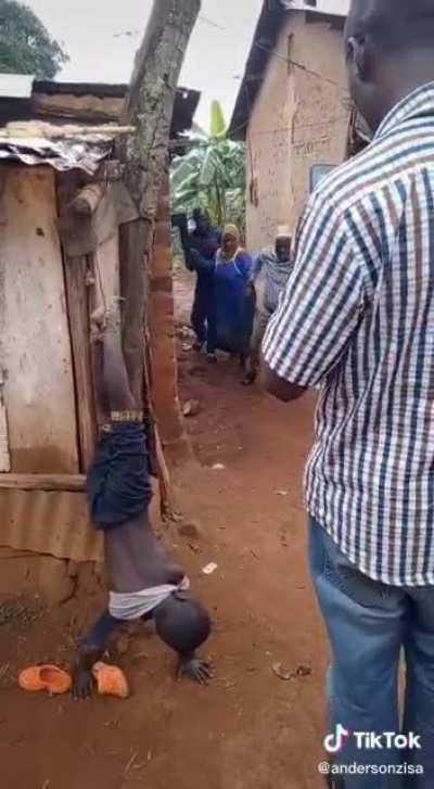 Uganda, East Africa. 10am in the rainy season. Woman administers this “punishment” to her orphaned stepson because he forgot to do dishes. He was there all night, got rescued in the morning after cries through the night.
