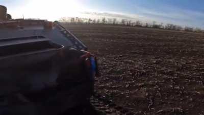 Ukrainian soldiers advancing behind armored vehicles in an open field. 2022