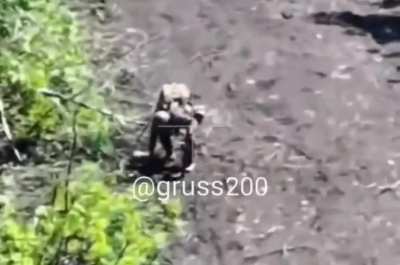 A curious russian inspects a bag of some kind on a road, after which it blows up.