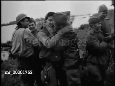Soviet and American soldiers meet at the Elbe river, hugging, and kiss. (1945)