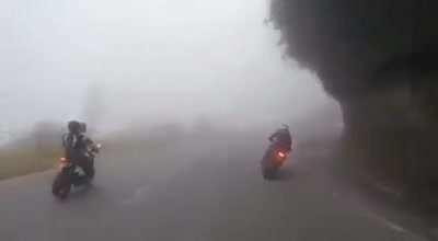 Group of motorcyclists speeding down a foggy mountain road, with very predictable results