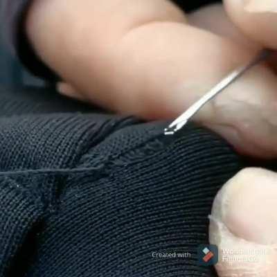 Small bodkin being used to repair run in knit material.
