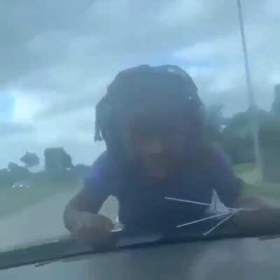 child hanging on to a car windshield going for a ride