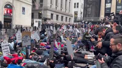 People hold tombstone signs and stage a die-in outside the New York Stock Exchange during a ‘March to Stop the Cuts’ protest.